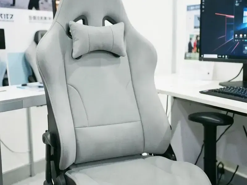 明るいブースに置かれた淡いグレーのゲームチェアとモニタ